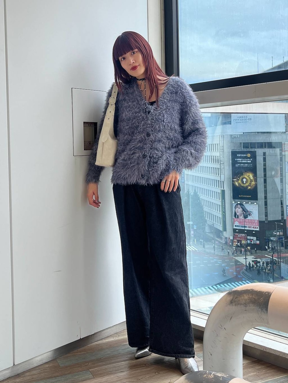 ホワイト系のショルダーバッグ、シルバー系のブーツ、ブラック系のデニムパンツを着用したレディースの秋コーディネートの6枚目の写真