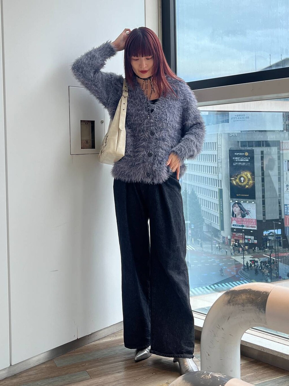 ホワイト系のショルダーバッグ、シルバー系のブーツ、ブラック系のデニムパンツを着用したレディースの秋コーディネートの4枚目の写真