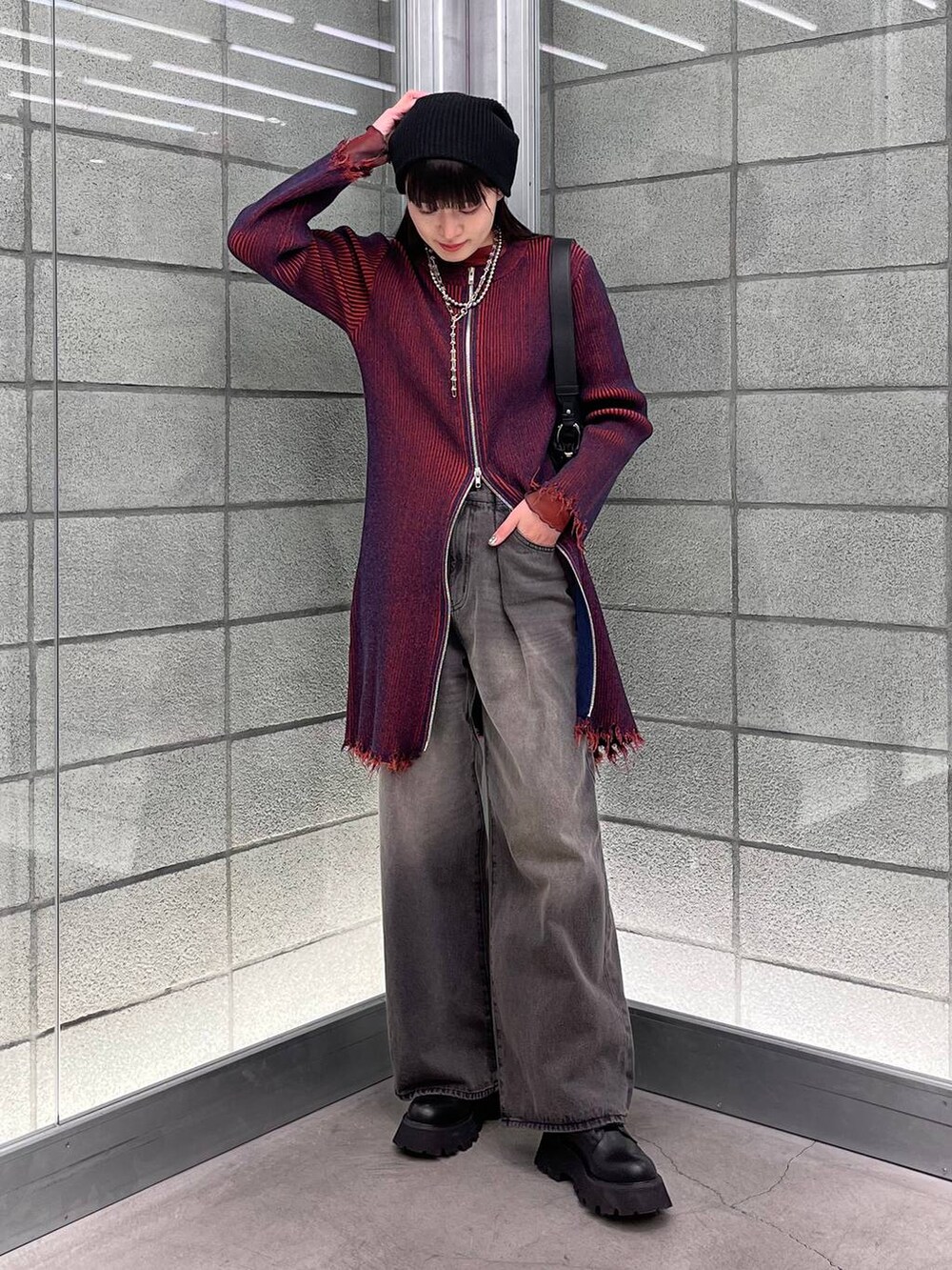 レッド系のワンピース、ブラック系のデニムパンツ、ブラック系のショルダーバッグを着用したレディースの冬コーディネートの4枚目の写真