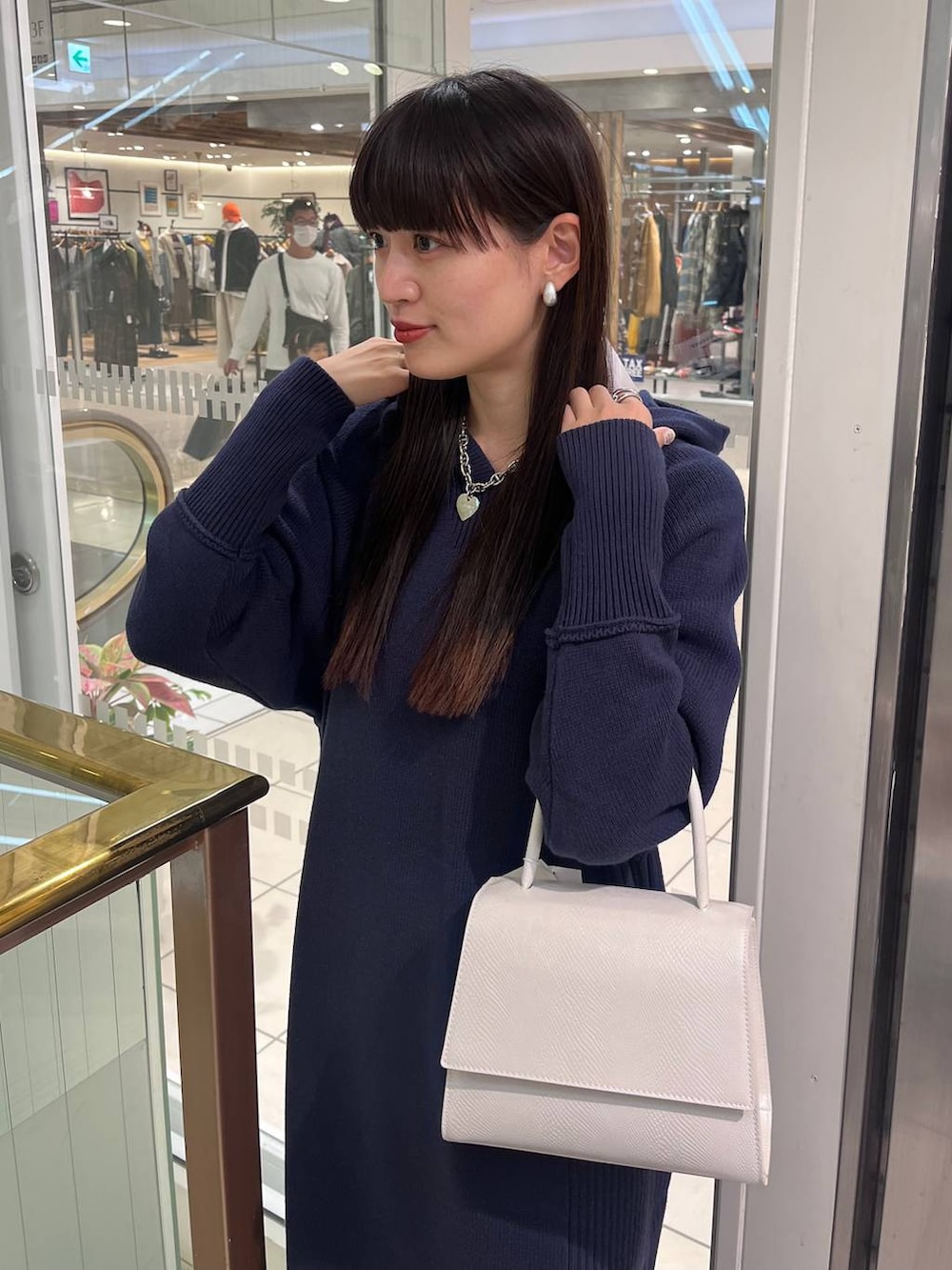 ホワイト系のハンドバッグ、ブラック系のブーツ、ブルー系のワンピースを着用したレディースの秋コーディネートの8枚目の写真