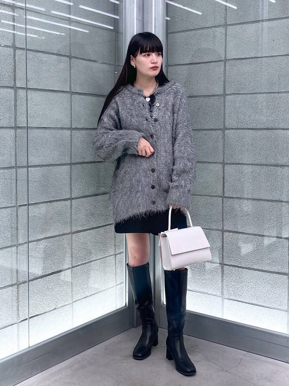 グレー系のカーディガン/ボレロ、ホワイト系のハンドバッグ、ブラック系のその他パンツを着用したレディースの秋コーディネートの5枚目の写真