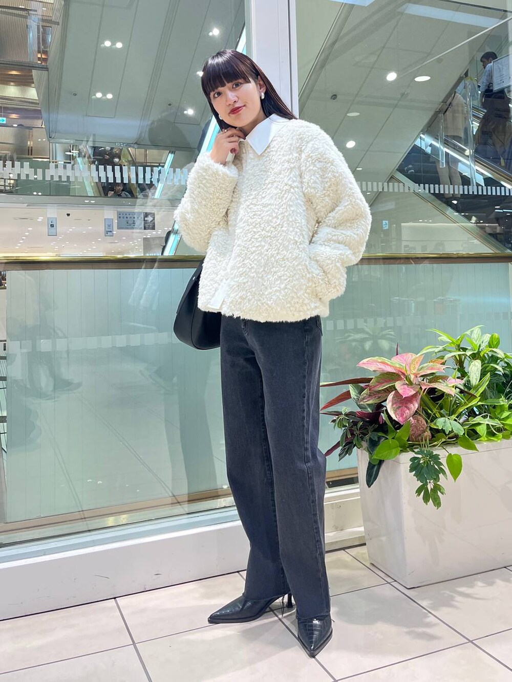 ブラック系のデニムパンツ、ブラック系のショルダーバッグ、ブラック系のブーツを着用したレディースの秋コーディネートの3枚目の写真