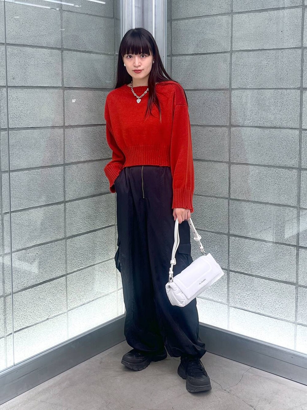 ブラック系のカーゴパンツ、ホワイト系のショルダーバッグ、レッド系のニット/セーターを着用したレディースの秋コーディネートの5枚目の写真