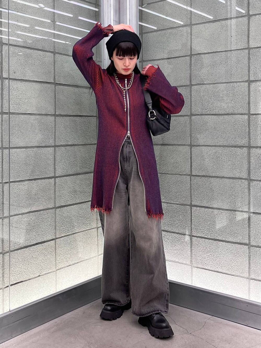 レッド系のワンピース、ブラック系のデニムパンツ、ブラック系のショルダーバッグを着用したレディースの冬コーディネートの6枚目の写真