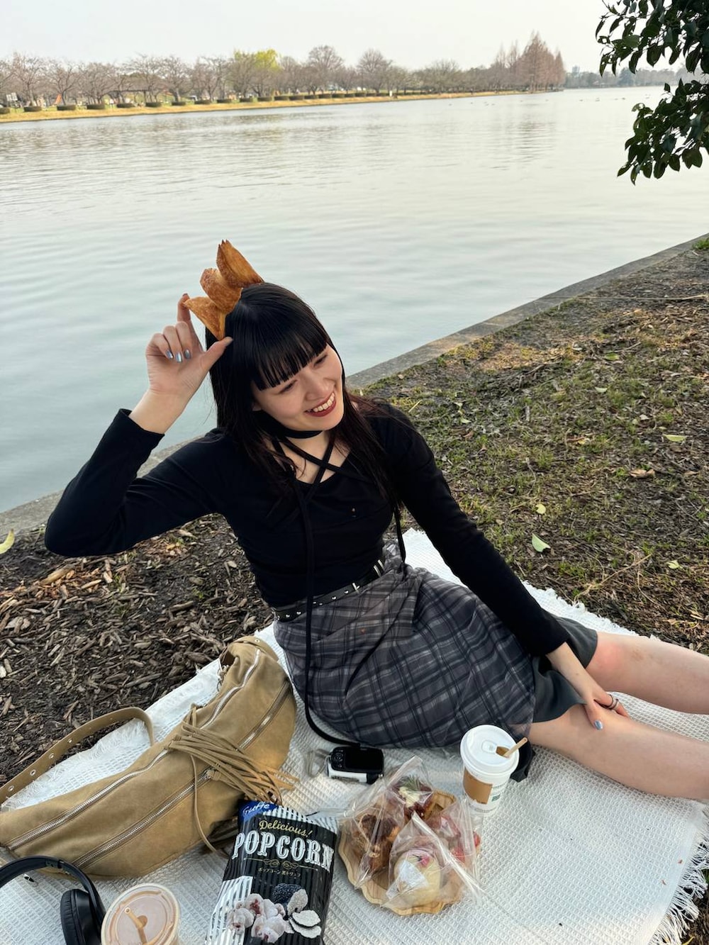 グリーン系のブーツ、ブラック系のスカート、ベージュ系のショルダーバッグを着用したレディースの春コーディネートの3枚目の写真