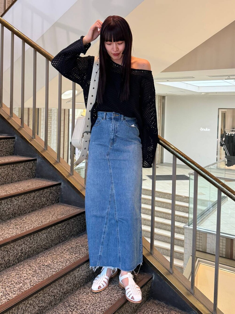 ブルー系のデニムスカート、ホワイト系のショルダーバッグ、ブルー系のニット/セーターを着用したレディースの春コーディネートの4枚目の写真