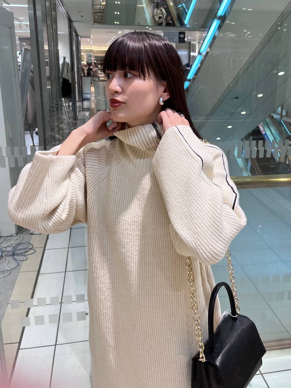 ブラック系のハンドバッグ、ブラック系のブーツ、ホワイト系のワンピースを着用したレディースの秋コーディネートの7枚目の写真