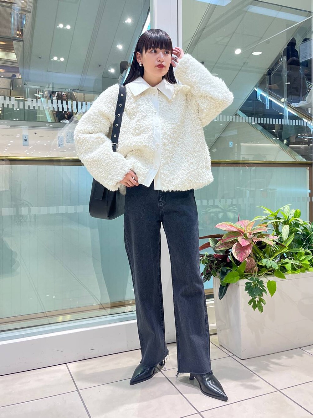 ブラック系のデニムパンツ、ブラック系のショルダーバッグ、ブラック系のブーツを着用したレディースの秋コーディネートの2枚目の写真