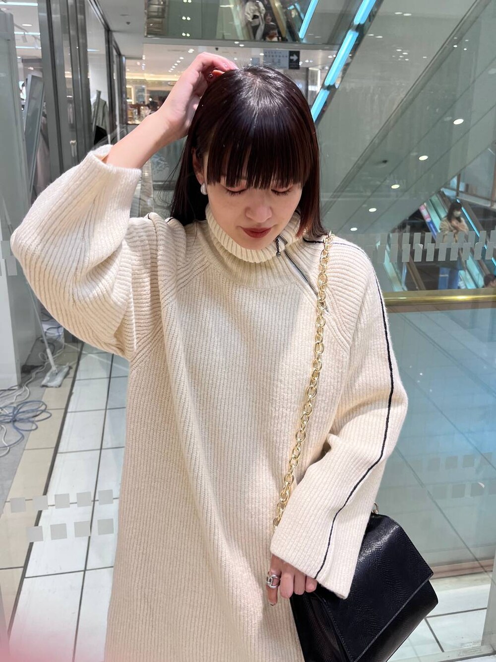 ブラック系のハンドバッグ、ブラック系のブーツ、ホワイト系のワンピースを着用したレディースの秋コーディネートの6枚目の写真