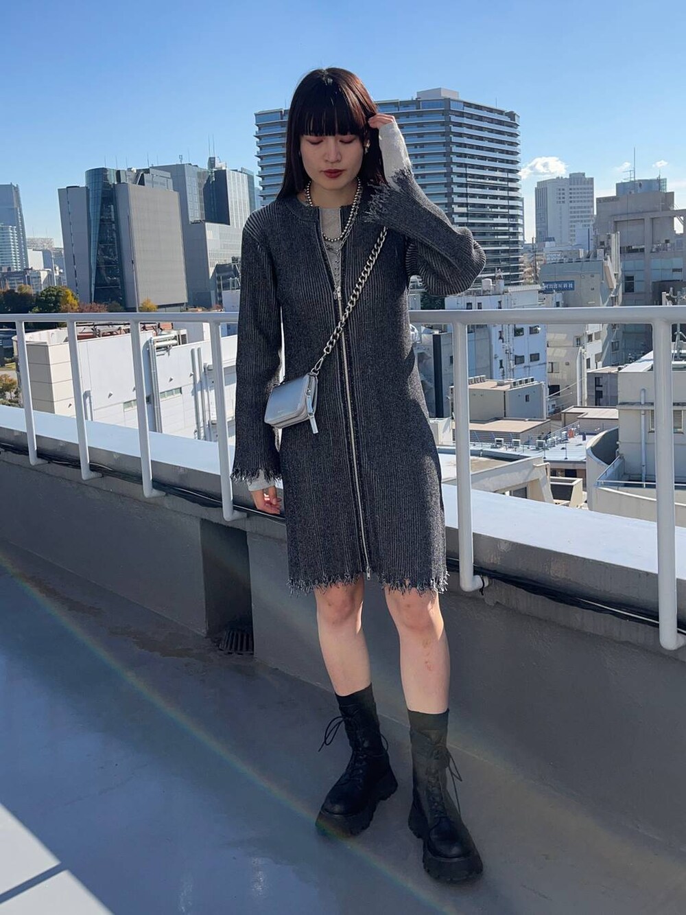 ブラック系のブーツ、ブラック系のワンピース、シルバー系のネックレスを着用したレディースの冬コーディネートの2枚目の写真