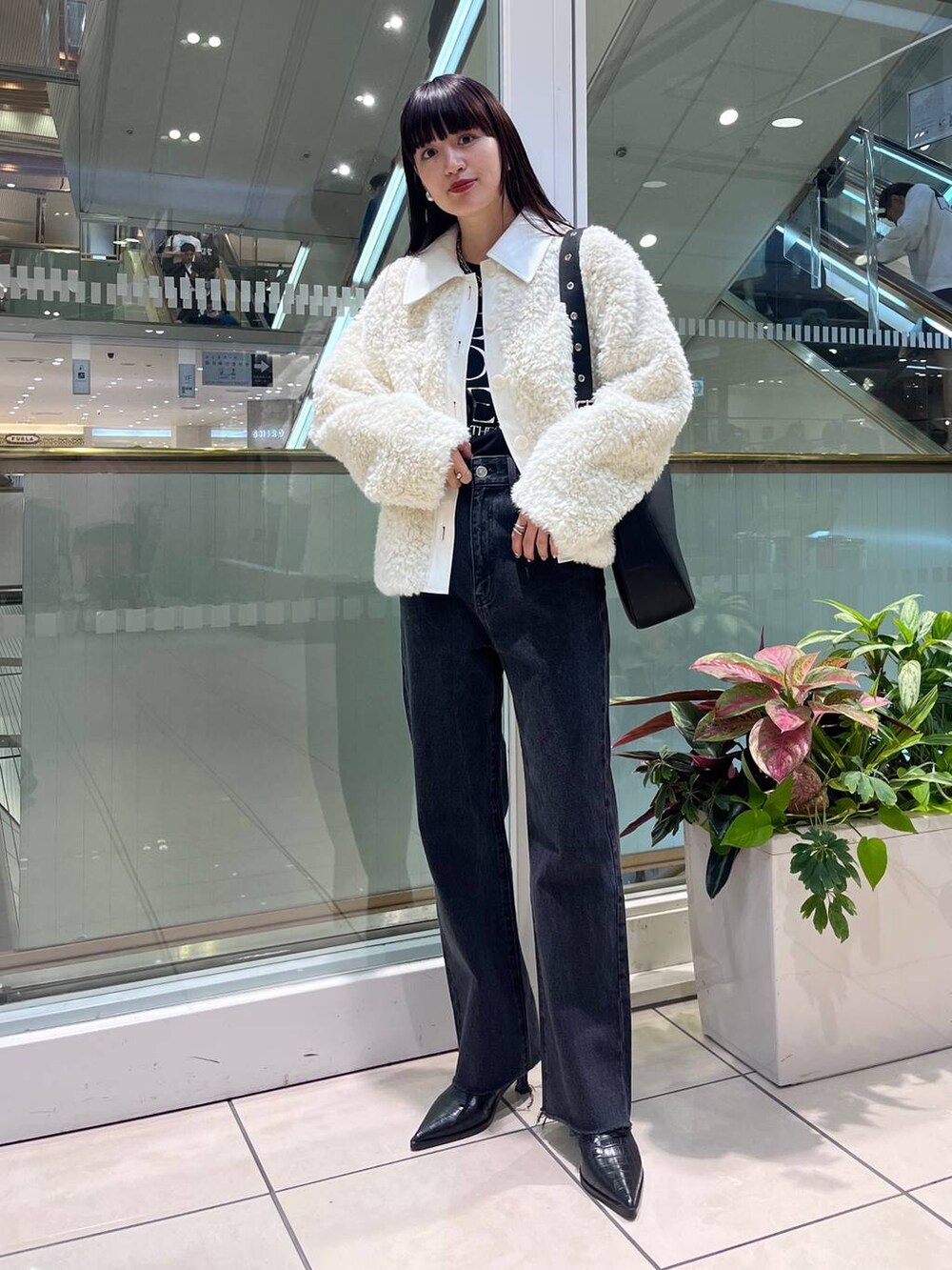 ブラック系のデニムパンツ、ブラック系のショルダーバッグ、ブラック系のブーツを着用したレディースの秋コーディネートの5枚目の写真