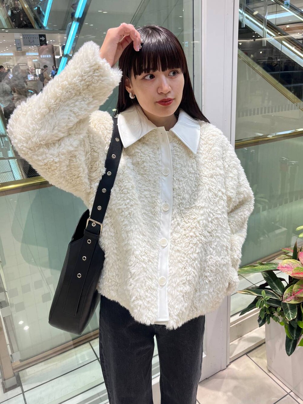 ブラック系のデニムパンツ、ブラック系のショルダーバッグ、ブラック系のブーツを着用したレディースの秋コーディネートの6枚目の写真