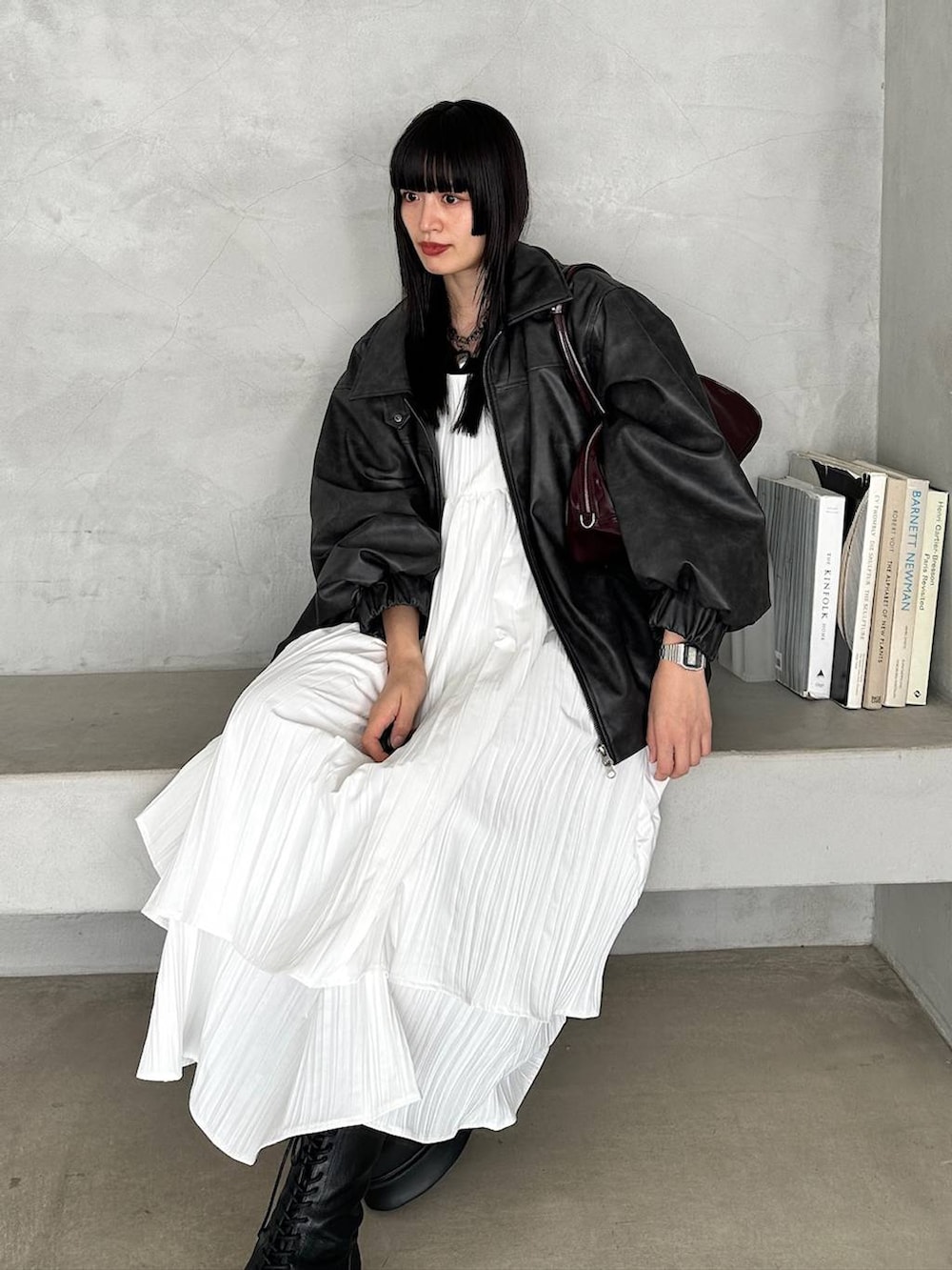 レッド系のボストンバッグ、ブラック系のブーツ、ホワイト系のワンピースを着用したレディースの冬コーディネートの5枚目の写真