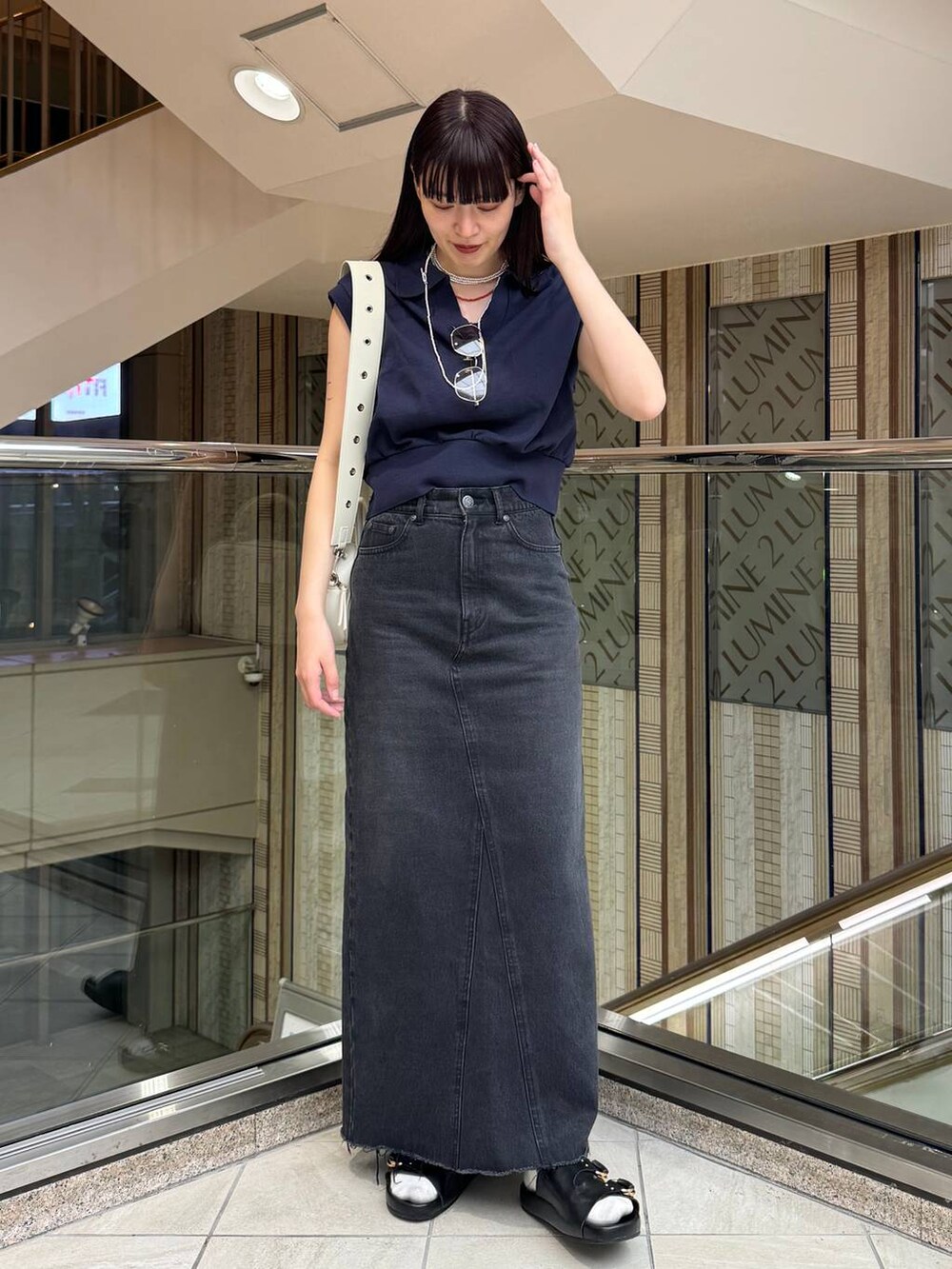 ブルー系のデニムスカート、ブラック系のサンダル、ブルー系のTシャツ/カットソーを着用したレディースの春コーディネートの3枚目の写真