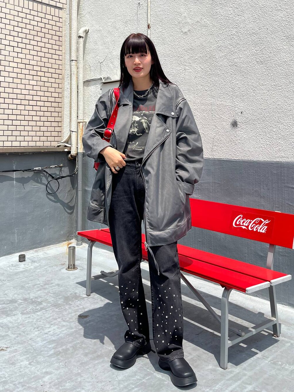 シルバー系のショルダーバッグ、ブラック系のTシャツ/カットソー、グレー系のライダースジャケットを着用したレディースの夏コーディネートの2枚目の写真