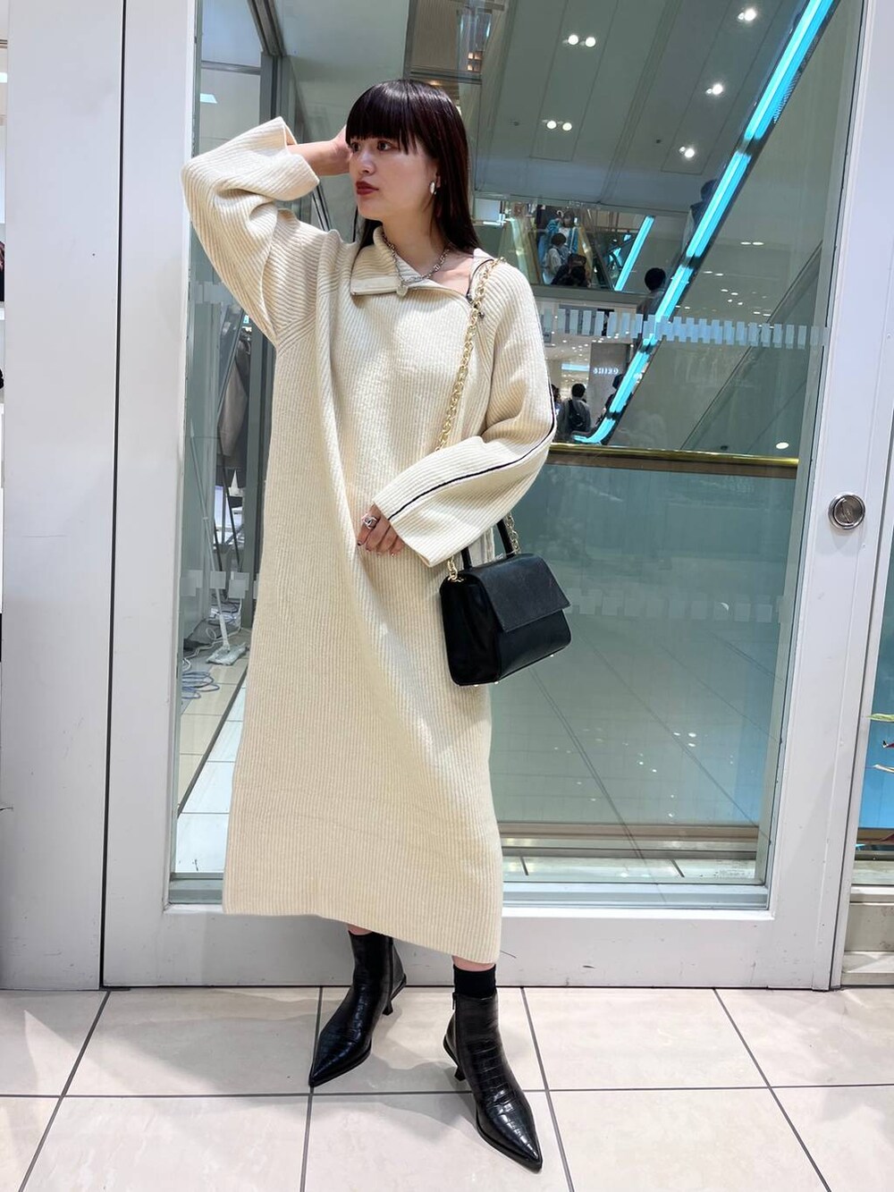 ブラック系のハンドバッグ、ブラック系のブーツ、ホワイト系のワンピースを着用したレディースの秋コーディネートの4枚目の写真