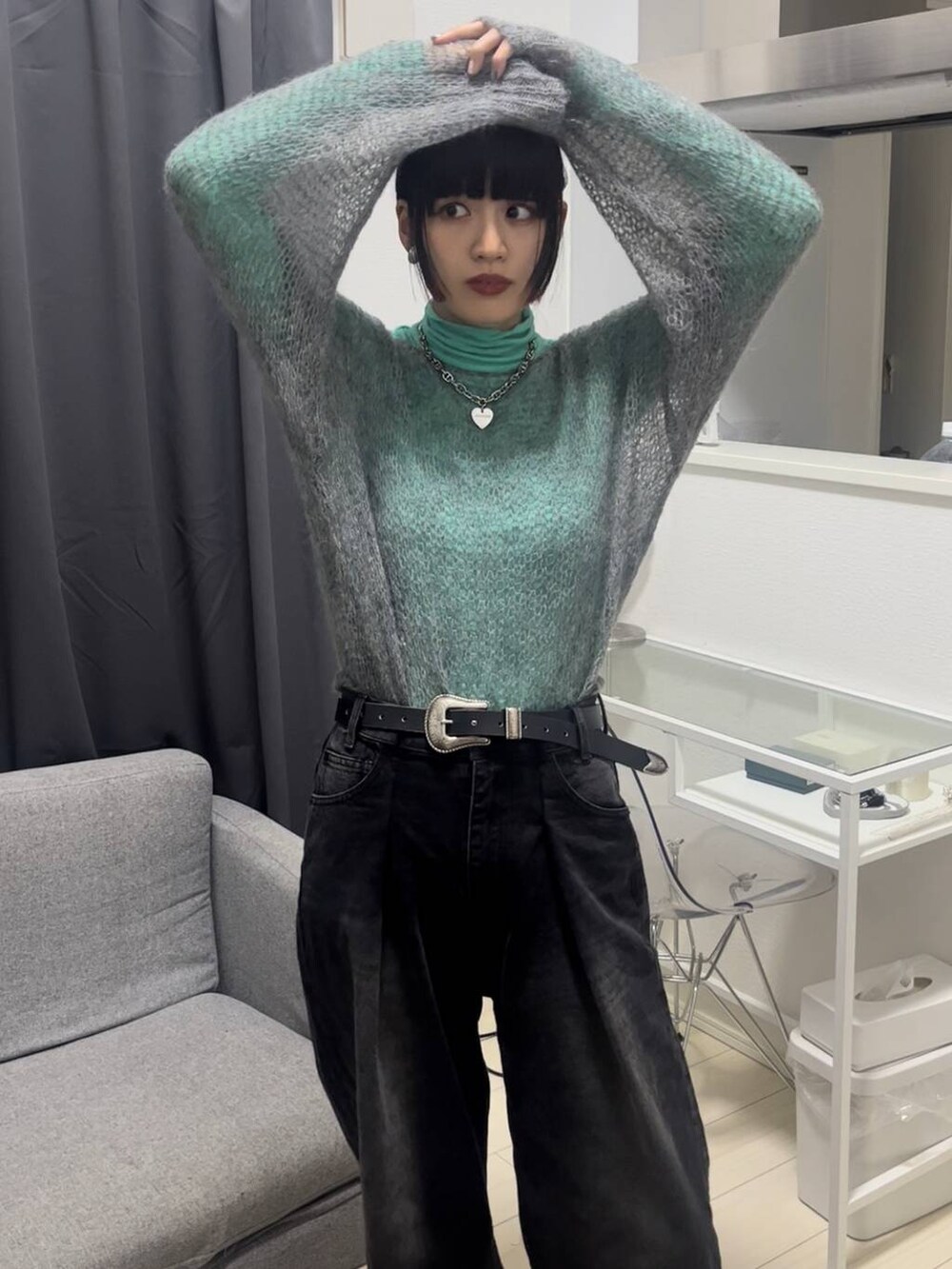 ブラック系のデニムパンツ、グレー系のニット/セーター、シルバー系のネックレスを着用したレディースの秋コーディネートの4枚目の写真