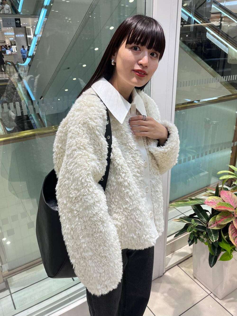 ブラック系のデニムパンツ、ブラック系のショルダーバッグ、ブラック系のブーツを着用したレディースの秋コーディネートの7枚目の写真