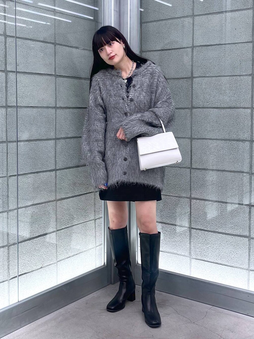 グレー系のカーディガン/ボレロ、ホワイト系のハンドバッグ、ブラック系のその他パンツを着用したレディースの秋コーディネートの4枚目の写真