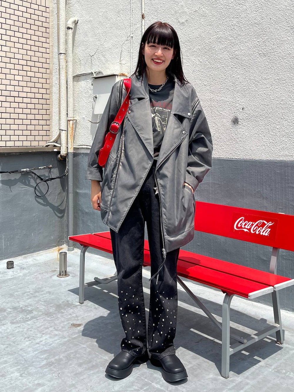 シルバー系のショルダーバッグ、ブラック系のTシャツ/カットソー、グレー系のライダースジャケットを着用したレディースの夏コーディネートの4枚目の写真