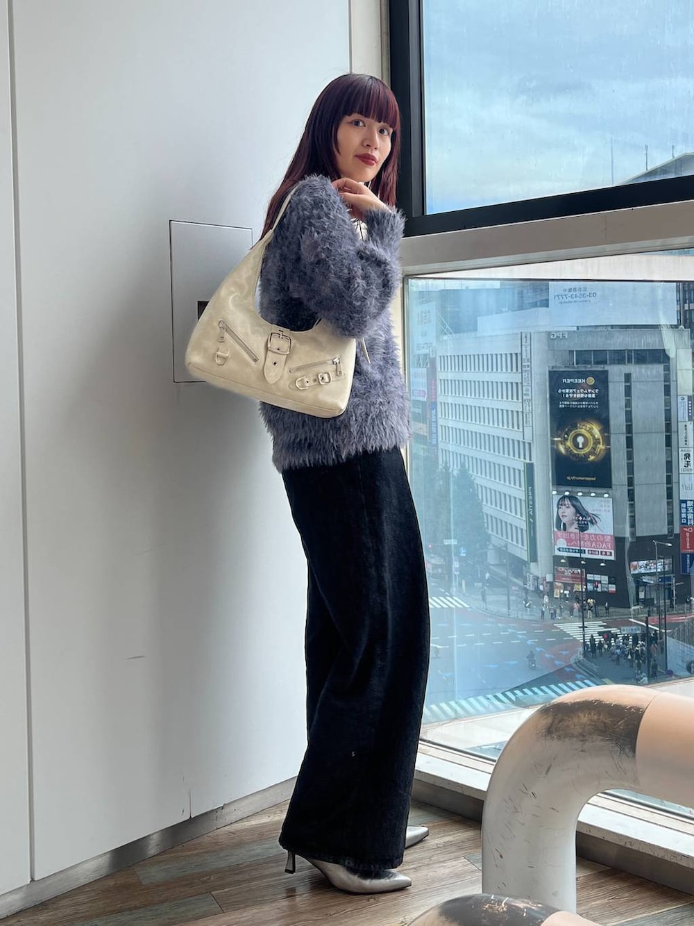 ホワイト系のショルダーバッグ、シルバー系のブーツ、ブラック系のデニムパンツを着用したレディースの秋コーディネートの5枚目の写真