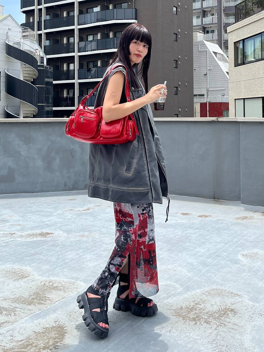 ブラック系のサンダル、レッド系のショルダーバッグ、レッド系のスカートを着用したレディースの夏コーディネートの5枚目の写真