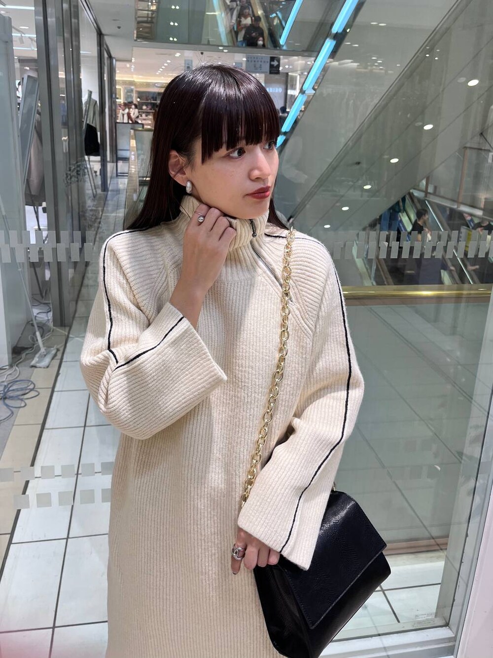 ブラック系のハンドバッグ、ブラック系のブーツ、ホワイト系のワンピースを着用したレディースの秋コーディネートの5枚目の写真