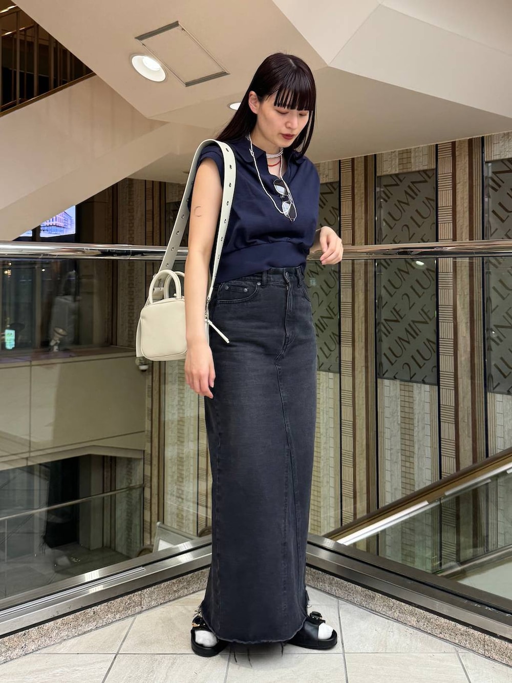 ブルー系のデニムスカート、ブラック系のサンダル、ブルー系のTシャツ/カットソーを着用したレディースの春コーディネートの2枚目の写真