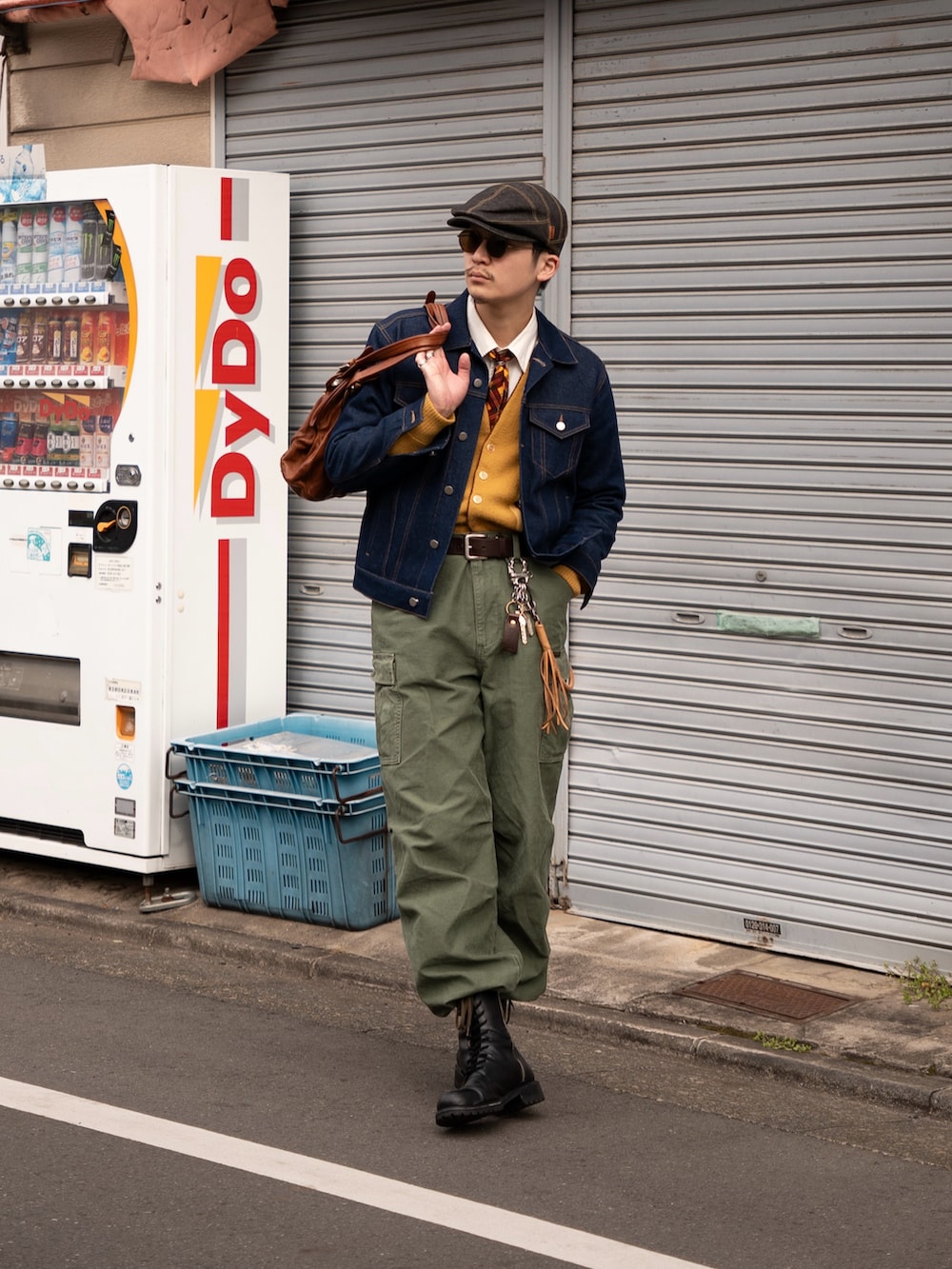 ブラウン系のボストンバッグ、ブラック系のブーツ、グリーン系のカーゴパンツを着用したメンズの春コーディネートの2枚目の写真