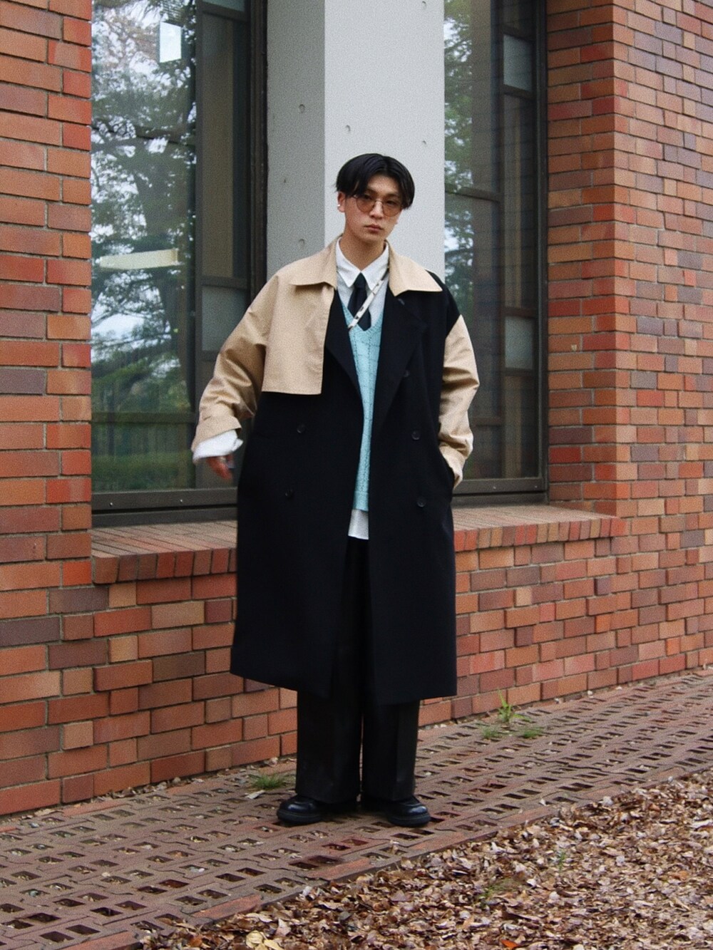 ブラック系のトレンチコート、ブルー系のベスト、ブラック系のドレスシューズを着用したメンズの春コーディネートの2枚目の写真