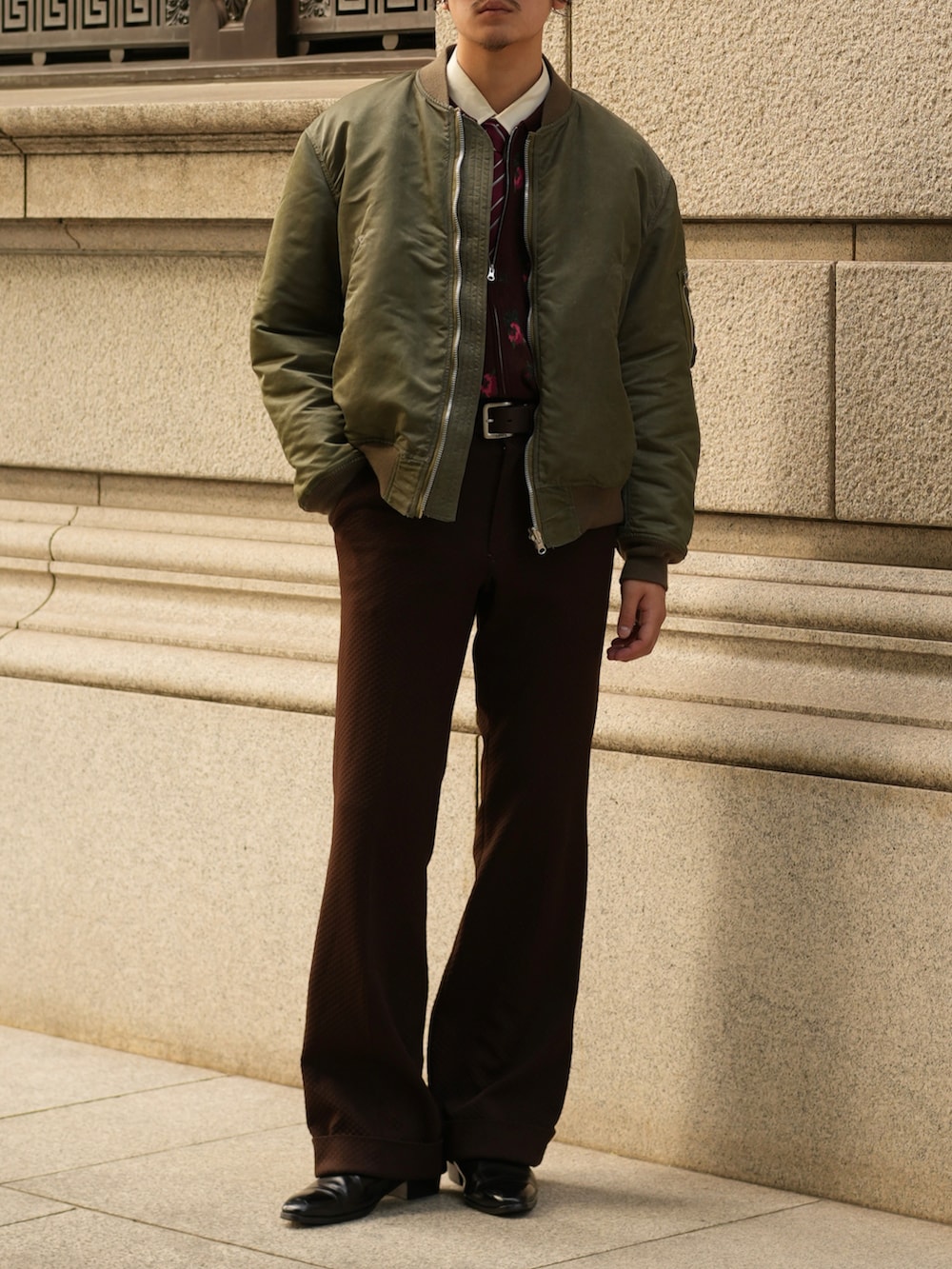 ブラウン系のスラックス、ブラック系のブーツ、グリーン系のMA-1を着用したメンズの秋コーディネートの5枚目の写真