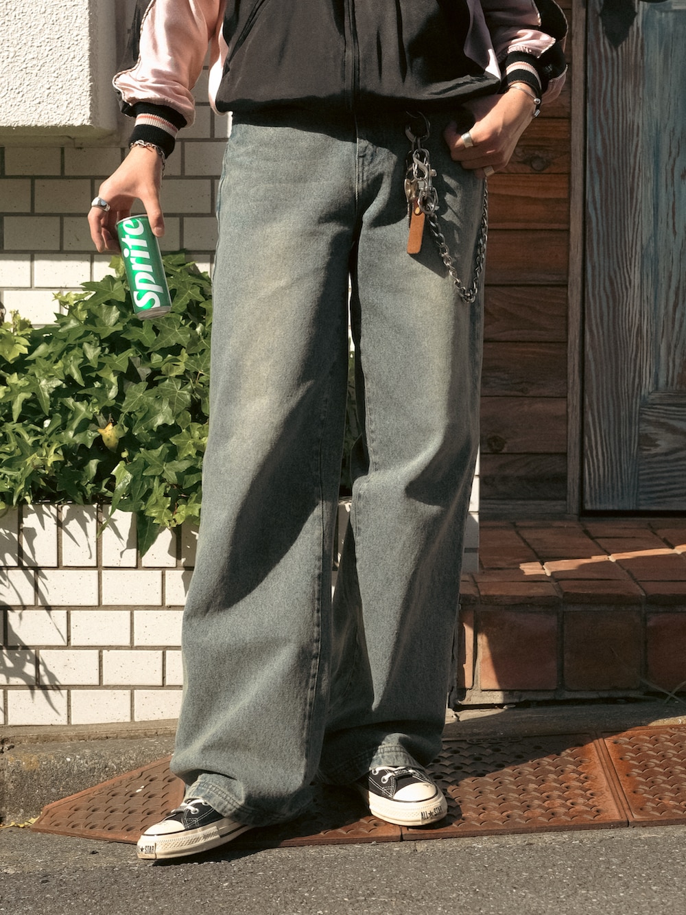 ブルー系のデニムパンツ、ブラック系のスニーカー、ブラック系のスタジャンを着用したメンズの春コーディネートの4枚目の写真