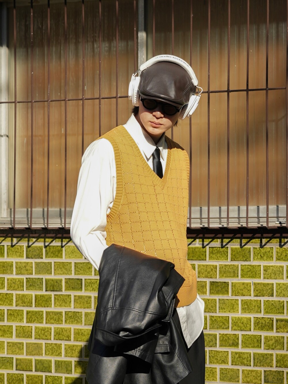 イエロー系のベスト、ブラック系のその他パンツ、ブラック系のシューズを着用したメンズの春コーディネートの3枚目の写真