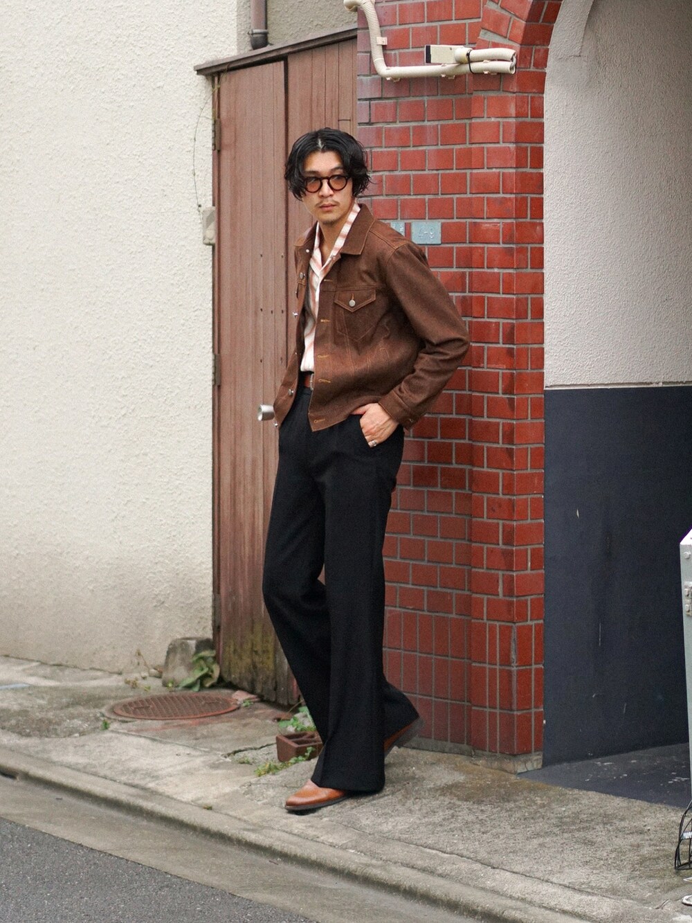 ブラック系のスラックス、ブラウン系のショルダーバッグ、ブラウン系のデニムジャケットを着用したメンズの秋コーディネートの2枚目の写真