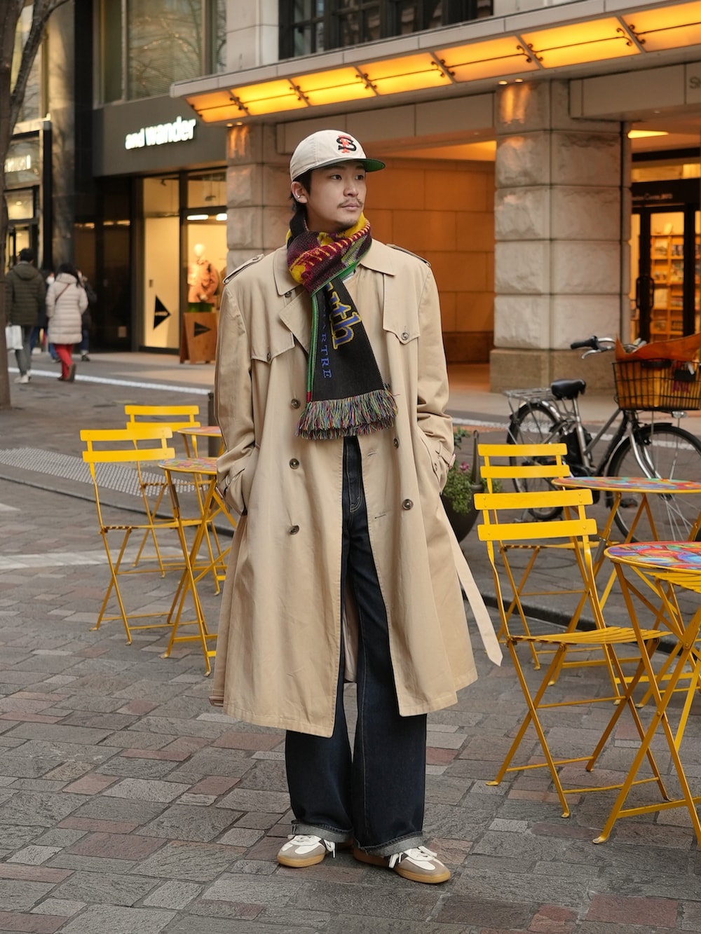 ホワイト系のスニーカー、ブルー系のデニムパンツ、ベージュ系のトレンチコートを着用したメンズの冬コーディネートの4枚目の写真