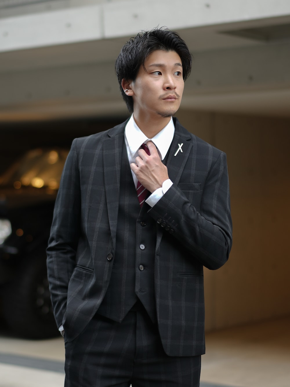 ブラック系のスーツセット、レッド系のネクタイ、ブラック系のブーツを着用したメンズの秋コーディネートの2枚目の写真