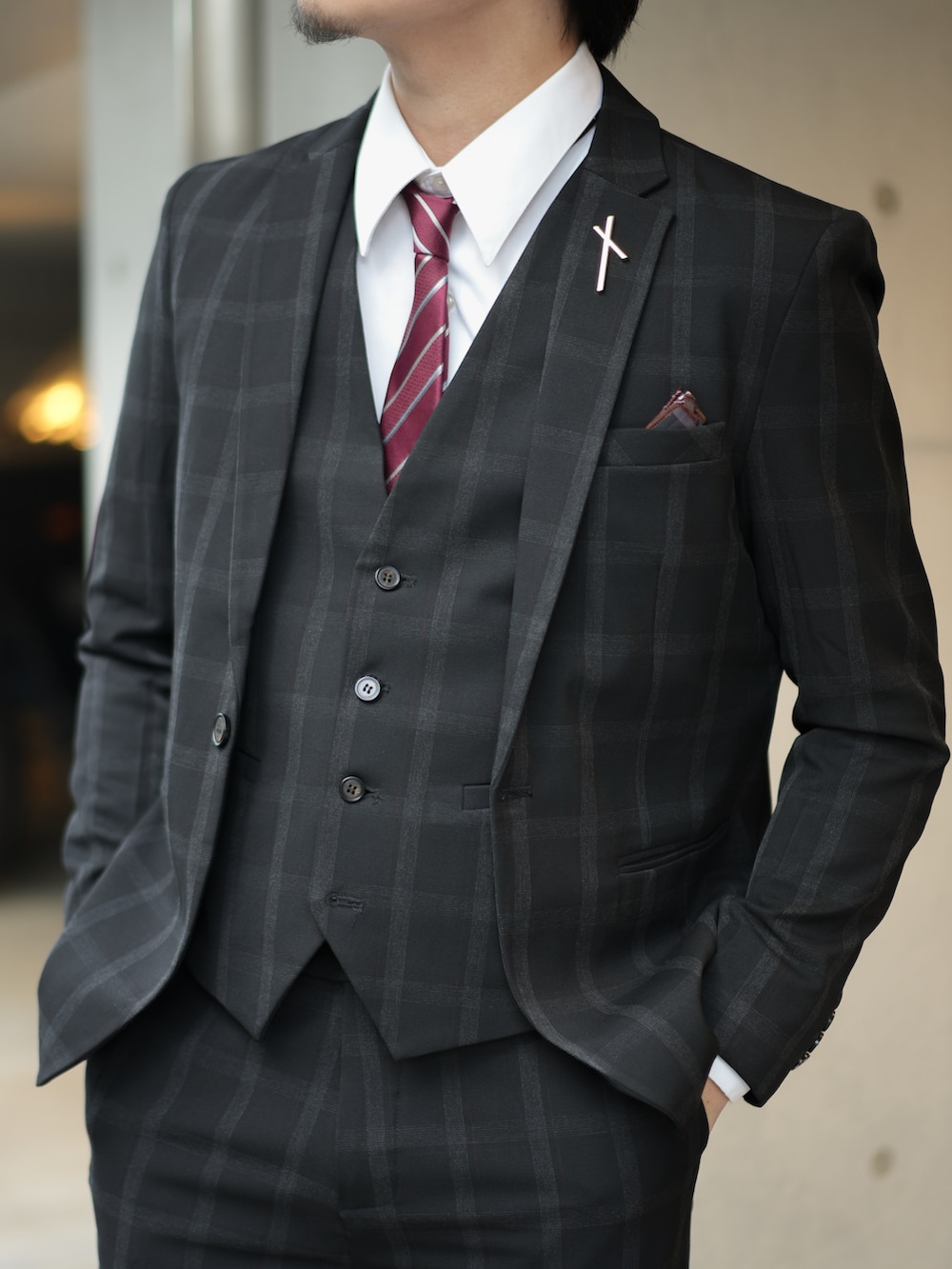 ブラック系のスーツセット、レッド系のネクタイ、ブラック系のブーツを着用したメンズの秋コーディネートの5枚目の写真