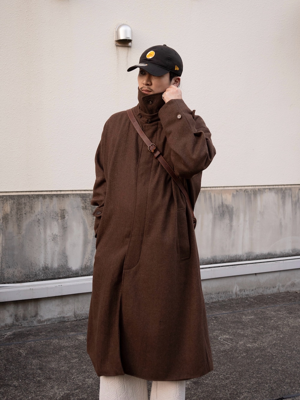 ブラウン系のステンカラーコート、ブラウン系のショルダーバッグ、ブラウン系のドレスシューズを着用したメンズの冬コーディネートの3枚目の写真