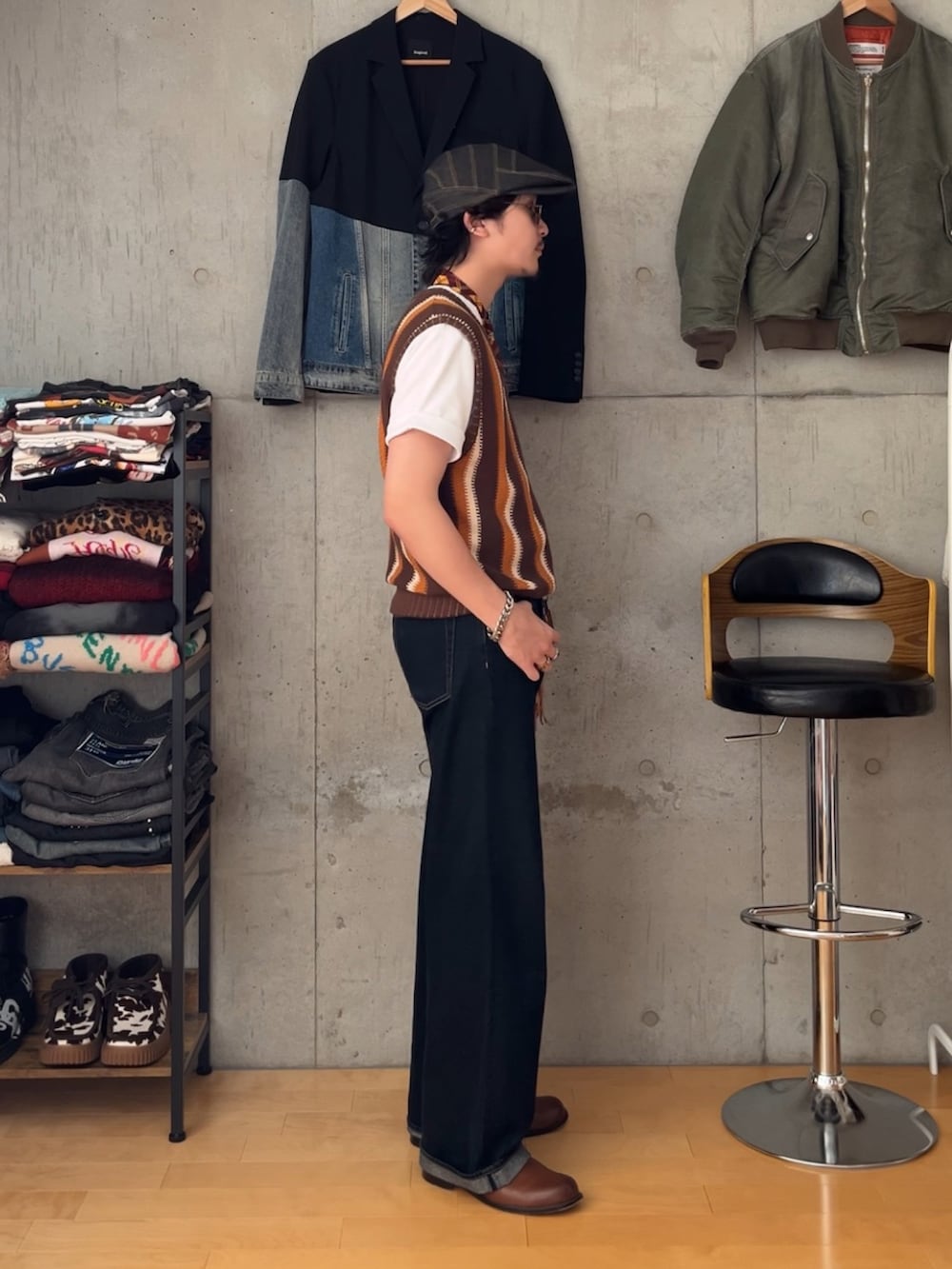 ブルー系のデニムパンツ、ブラウン系のベスト、ブラウン系のブーツを着用したメンズの夏コーディネートの2枚目の写真