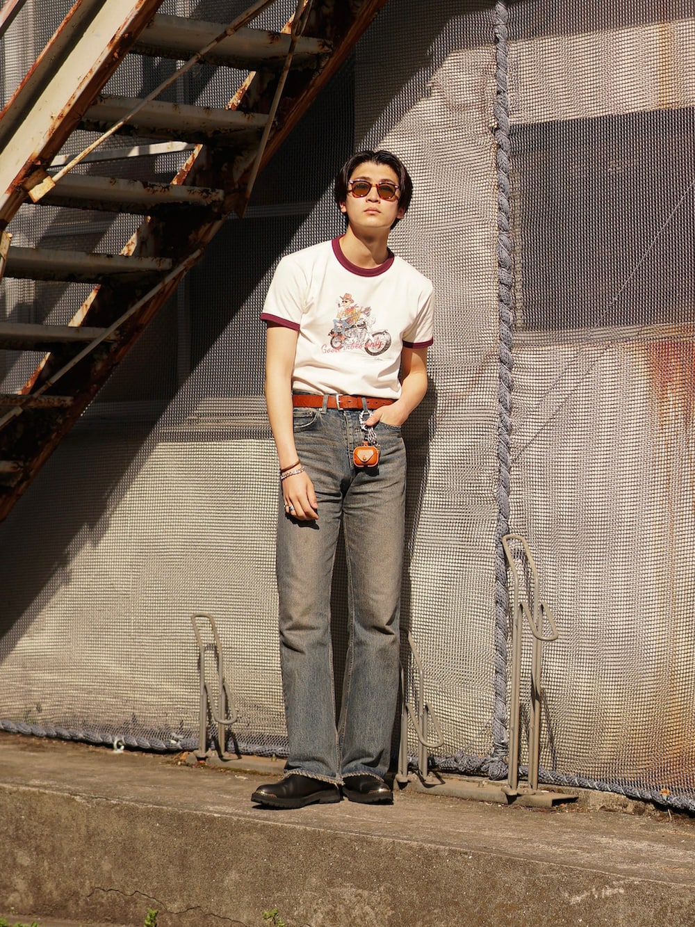 ブルー系のデニムパンツ、ブラック系のブーツ、レッド系のTシャツ/カットソーを着用したメンズの春コーディネートの4枚目の写真