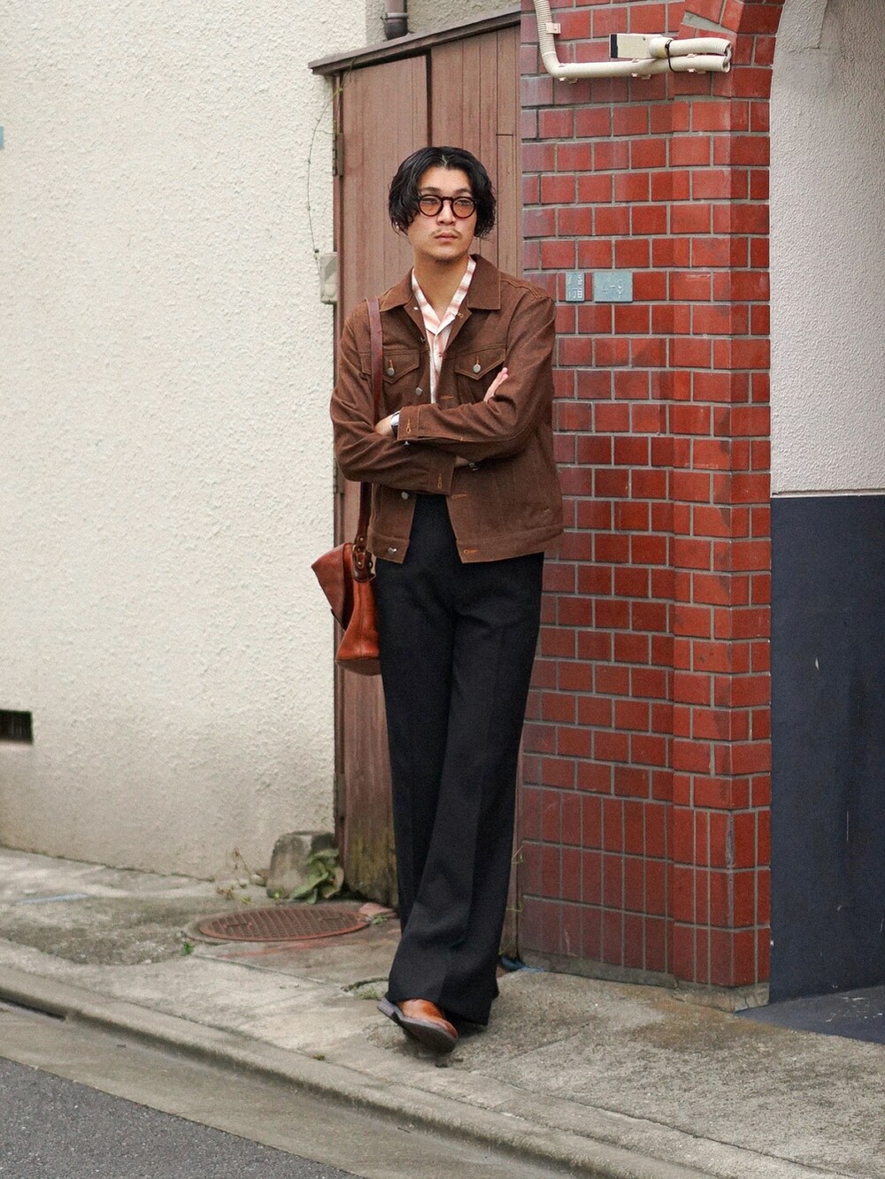 ブラック系のスラックス、ブラウン系のショルダーバッグ、ブラウン系のデニムジャケットを着用したメンズの秋コーディネートの5枚目の写真