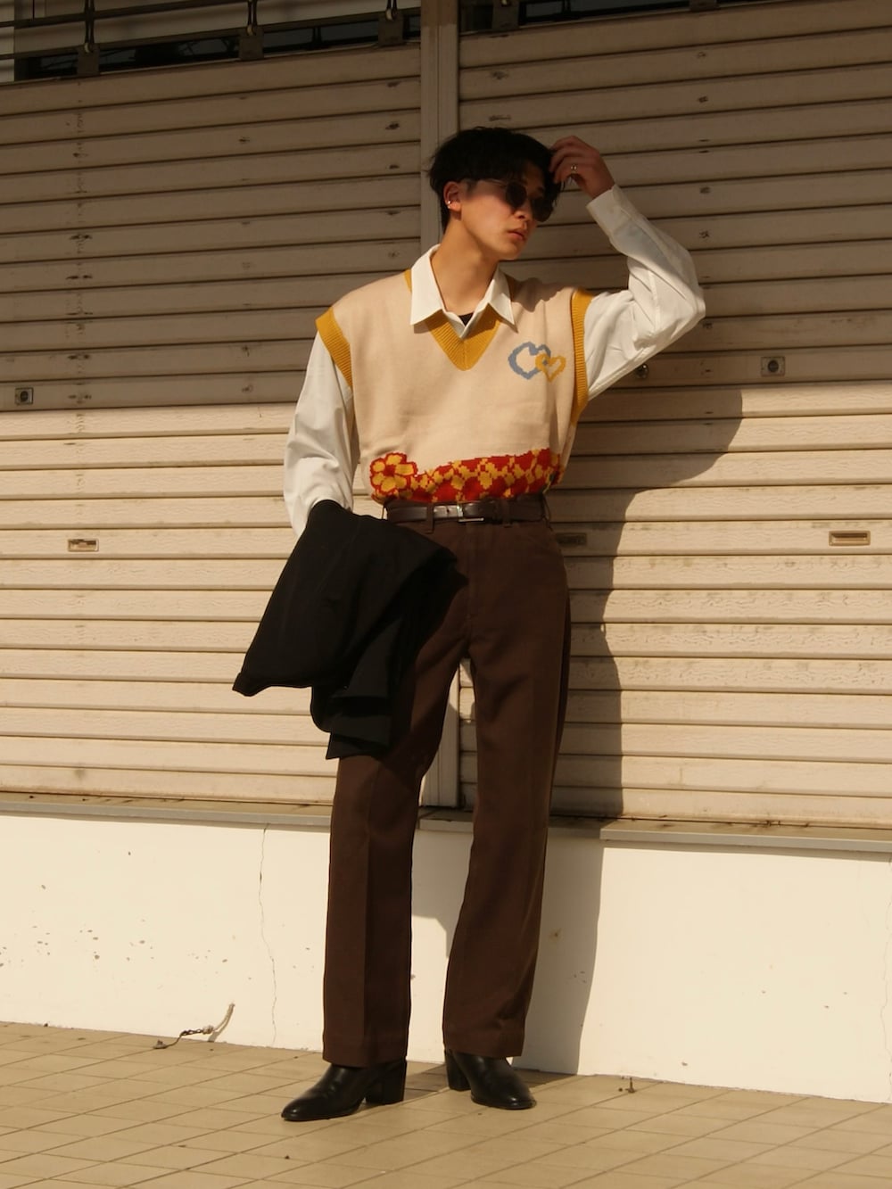 ブラウン系のデニムパンツ、ブラック系のドレスシューズ、イエロー系のベストを着用したメンズの春コーディネートの2枚目の写真