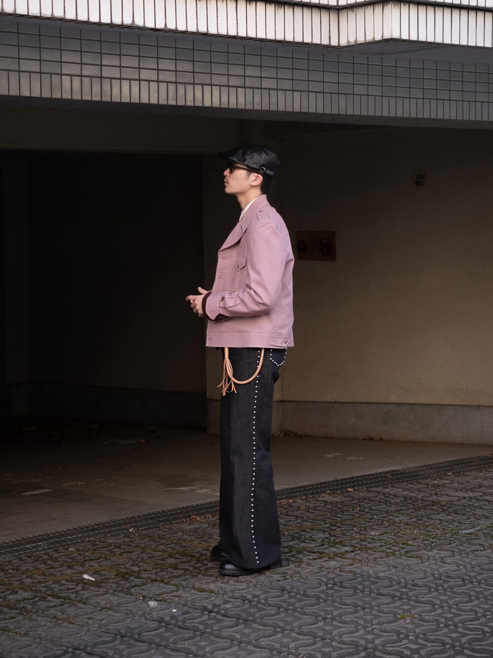 ブラック系のデニムパンツ、ピンク系のミリタリージャケット、ブラウン系のニット/セーターを着用したメンズの春コーディネートの3枚目の写真