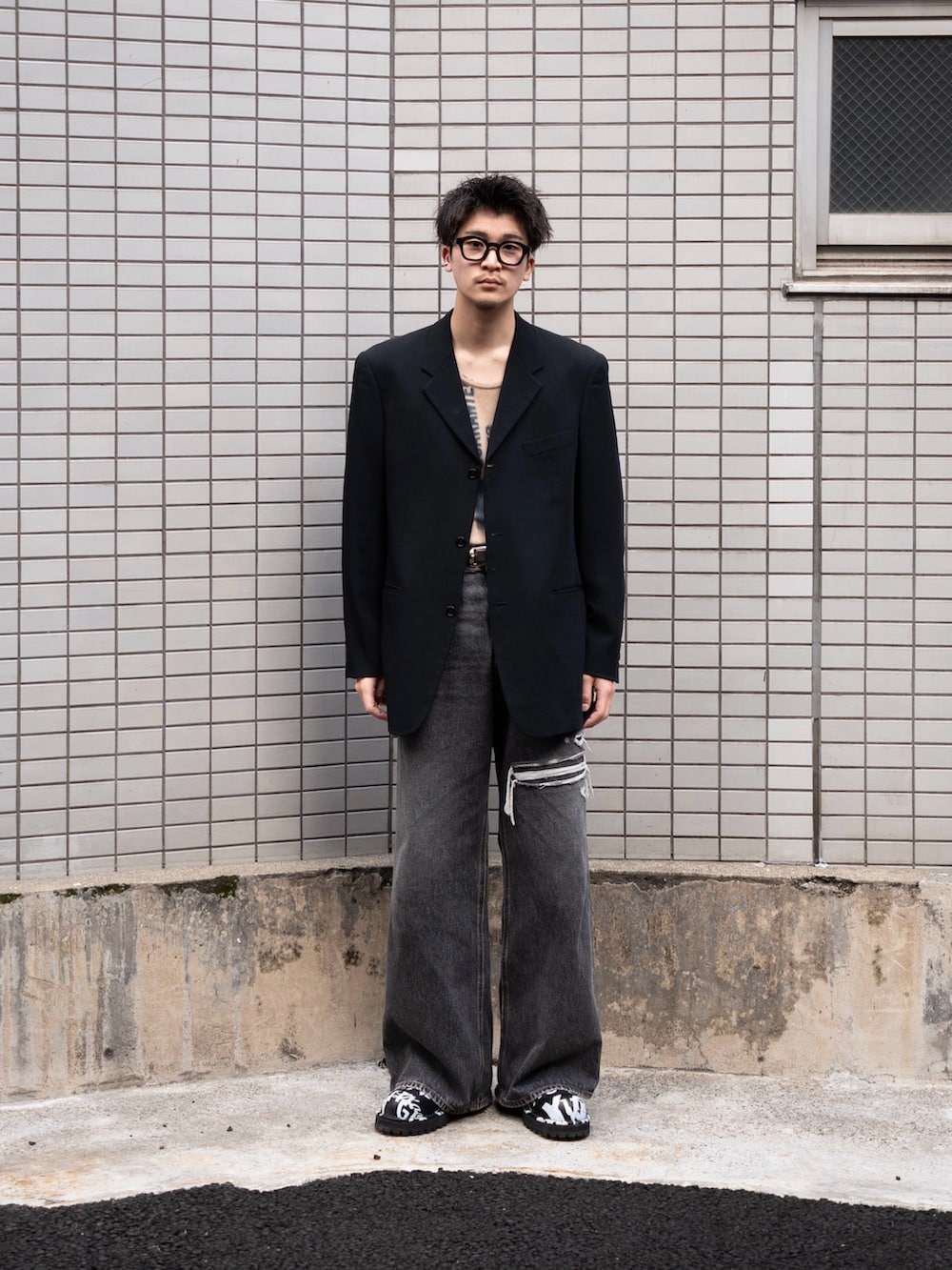 ブラック系のデニムパンツ、ブラック系のテーラードジャケット、ベージュ系のタンクトップを着用したメンズの冬コーディネートの4枚目の写真