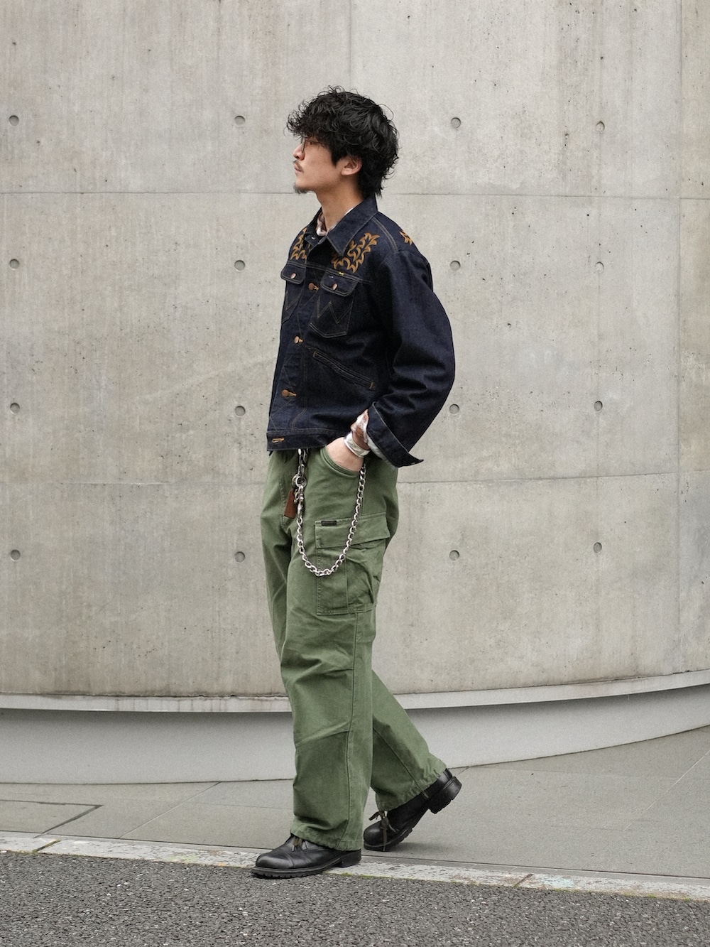 グリーン系のカーゴパンツ、ブラック系のブーツ、ブルー系のデニムジャケットを着用したメンズの春コーディネートの3枚目の写真