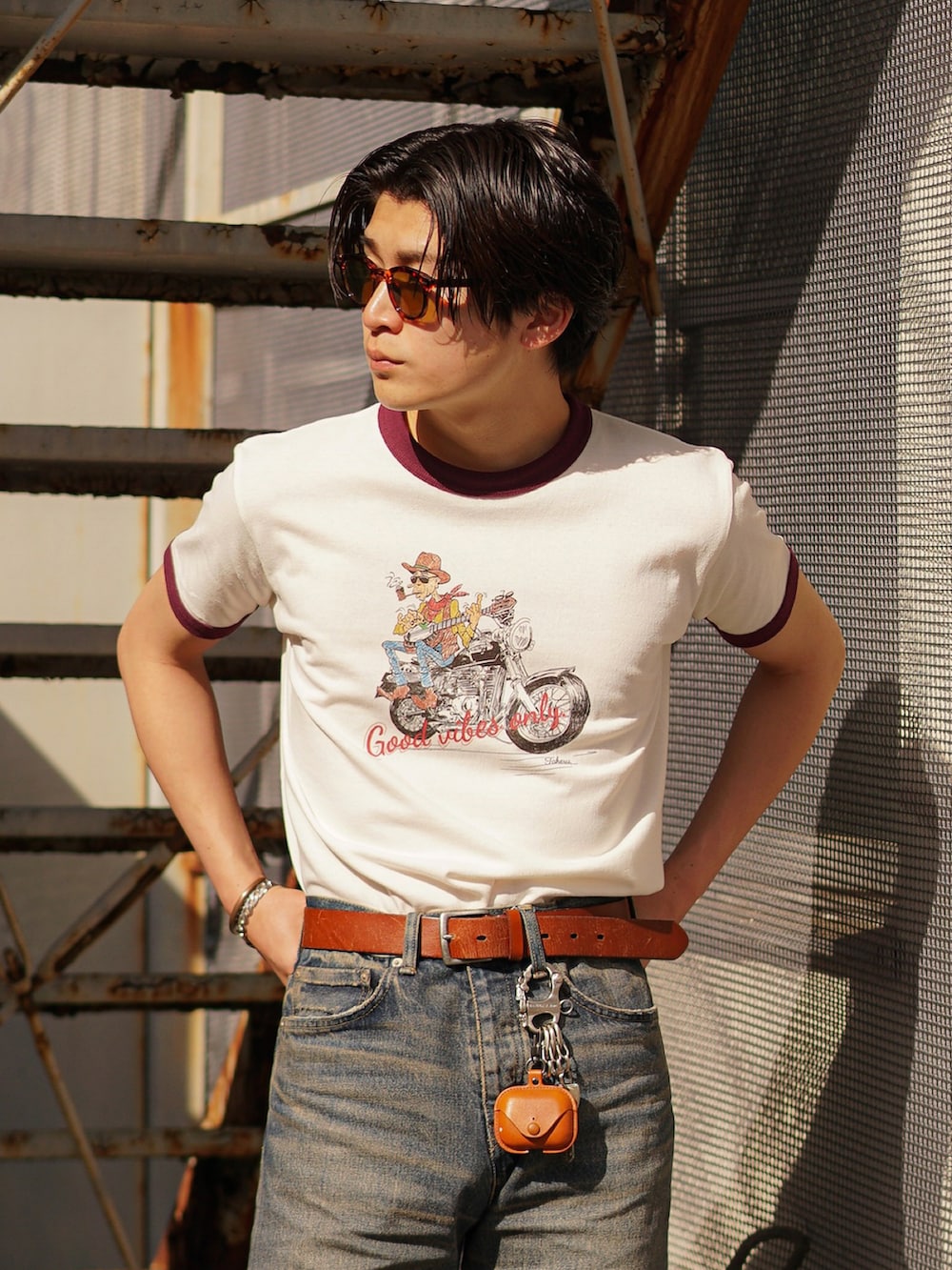 ブルー系のデニムパンツ、ブラック系のブーツ、レッド系のTシャツ/カットソーを着用したメンズの春コーディネートの2枚目の写真