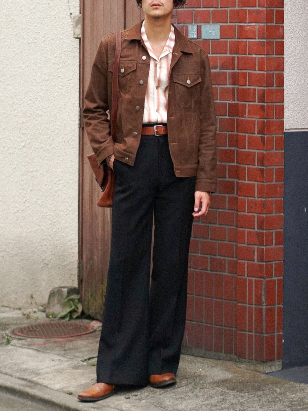 ブラック系のスラックス、ブラウン系のショルダーバッグ、ブラウン系のデニムジャケットを着用したメンズの秋コーディネートの4枚目の写真