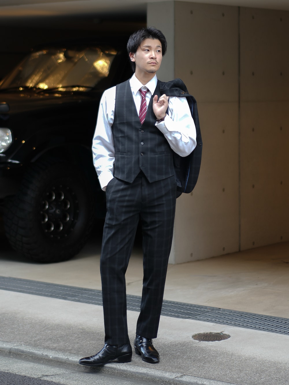 ブラック系のスーツセット、レッド系のネクタイ、ブラック系のブーツを着用したメンズの秋コーディネートの4枚目の写真