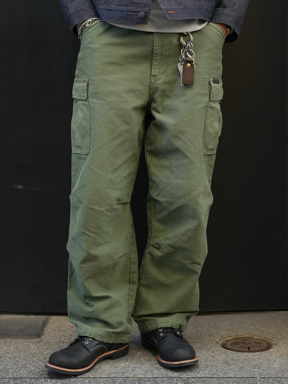 ブラック系のデニムジャケット、グリーン系のカーゴパンツ、ブラック系のブーツを着用したメンズの冬コーディネートの3枚目の写真