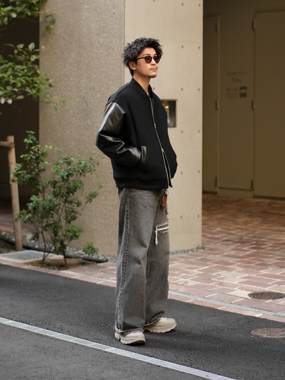 ブラック系のスタジャン、ブラック系のデニムパンツ、グレー系のスニーカーを着用したメンズの秋コーディネートの3枚目の写真
